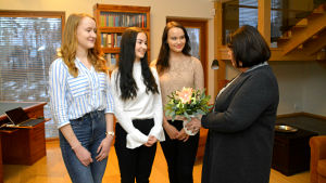 Aktiastiftelsens ordförande Ullrike Hjelt-Hansson överräcker blommor till årets luciatrio. Ullrike Hjelt-Hansson från Aktiastiftelsen kommer med blommor till luciatrion