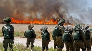 Israeliska soldater står intill en brand på ett vetefält nära en kibbutz intill Gazaremsan.