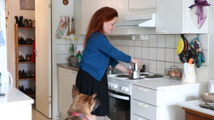 Lena har flera gånger kontaktat disponenten angående problem med inomhusluften. Lena Bengtson står i sitt kök och lagar kaffe. Hennes hund sitter bredvid henne på golvet och tittar på.