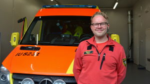 Akutvårdare Samuli Mäkelä är glad över den nya stationen. Akutvårdare ler framför en ambulans