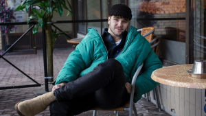 Lucas berättar att han ofta ifrågasatt om han valt fel bransch, men att han oavsett alltid landar på att musik är vad han vill jobba med. Han berättar att han får anstränga sig för att lära sig att jobba med sin introverta sida så att han orkar med jobbet. Lucas sitter på en uteservering med benen i kors och en stor vindjacka på sig. Han ser rakt in i kameran och ler. I bakgrunden syns ett palmträd i plast.