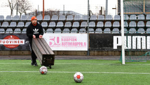 Koljonen följde med KuPS träningar i ett par månader efter skadan. Sedan blev frustrationen för intensiv. Pele Koljonen bär en bänk på en fotbollsplan.