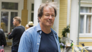 Kjell Westö är på inspelningsplatsen för att följa med hur det går. Han tycker att det är spännande att få se hur slutprodukten blir. En man i jeansjacka som ler.