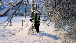 En cyklist leder sin cykel i snön.