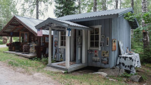 Kaksi mökkiä, ruskea ja vaaleansininen, ulkoseiniin kiinnitetty kuvia Elvis Presleystä. Sinisen tuvan kattoon kiinnitetty USA:n ja Suomen liput.