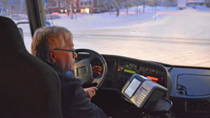 Jari Jaatinen kör hobbybussen. En man i medelåldern sitter bakom ratten på en buss. Det är mörkt i bussen, likaså utomhus. Ute synns en snötäckt gata.