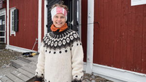 Virve Savoila känner starkt för Ekenäs Naturum. Kvinna i tjock tröja ser mot kameran och ler. I bakgrunden rött trämagasin.