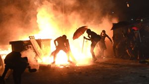 Demonstranterna har satt eld på fordon och byggnader under sammandrabbningar med polisen. Personer som antänt gatubränder i Hongkong.