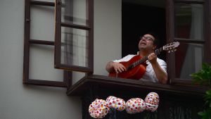 En man med sin gitarr i ett fönster i Sevilla Man sjunger och spelar i ett fönster i Sevilla