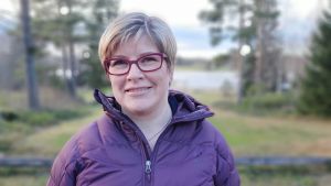 Det är myndigheterna som testar och besluter vad som sker ifall positiva fall påträffas på farmerna, säger Johanna Korpela. Kvinna i lila jacka och lila glasögon står utomhus och ser in i kameran med ett litet leende.