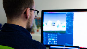 Till kodare Dan Huikos jobbuppgifter hör bland annat att planera, programmera och testa spel. En person sitter framför en dator och jobbar.