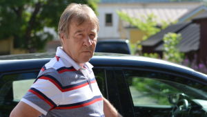 Den nya körkortslagen kräver mycket av eleverna, men också av utbildarna, säger trafiklärare Olavi Virranvuo En man som står utanför en svart bil. Man ser ganska lite av bilen, bara taket.