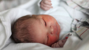 En snabb hemförlovning kan betyda att du åker hem mellan 6 och 36 timmar efter förlossningen beroende på diverse kriterier. Baby i säng.