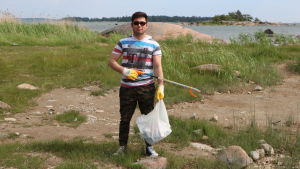Hassan Ahmedi har tillsammans med Röda Korsets sommarklubb kommit ut till stranden för att hjälpa Östersjön. Han tycker om talkoandan i sådana här projekt. Hassan Ahmedi poserar med skräpplockare på stranden han städar