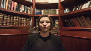 Poesi och skrivande har fungerat terapeutiskt för Hanna Lagerström. Hanna Lagerström sitter svartklädd i en mörk trästol med snirklat ryggstöd. I bakgrunden finns en bokhylla full med böcker.
