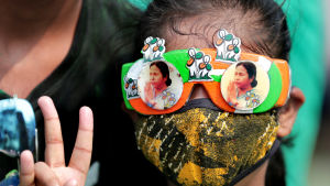 En anhängare till TMC-partiet i Västbengalen visade upp segertecknet, iklädd glasögon prydda av porträtt på partiledaren Mamata Banerjee. En anhängare till TMC-partiet i Västbengalen visade upp segertecknet, iklädd glasögon prydda av porträtt på partiledaren Mamata Banerjee.