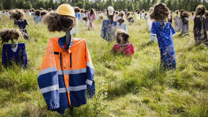 Många yrkesgrupper är representerade ute på fältet. Hiljaisen kansan heinäpäinen hahmo päällään rakennustyöntekijän takki ja keltainen kypärä.