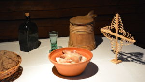 Grisfötter, brännvin, öl och ett Tomaskors på ett julbord. Det här hade lite mer välbärgade invånare råd med. Julbord på Klosterbackens hantverkarmuseum, på bordet står ett levande ljus, julöl, grisfötter och ett tomaskors.