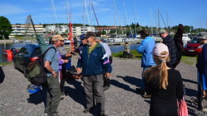 De flesta av tävlingsdeltagarna känner varandra. En grupp människor står och pratar i solen vid Borgå å.