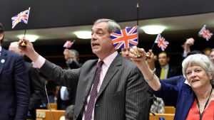 Nigel Farage från Brexitpartiet firar brexit i Europaparlamentet. Nigel farage håller upp en brittisk flagga.