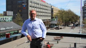 Max Jansson undrar vad det här kommer att kosta samhället. Man i ljusblå skjorta står lutad mot ett balkongräcke.