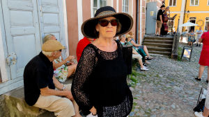 Monica Rosendahl är en van besökare på Avantis sommarfestival. En kvinna står framför ett rosa hus och människor sitter bakom henne.