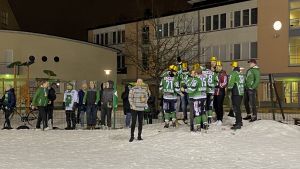 Guldhattarna åkte på redan innan matchens sista minuter var slut. Flera personer i gröna skjortor och guldhattar står nära varandra, synbart glada. Några kramas.