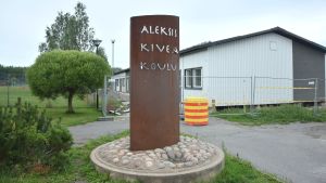 I Sjundeå bygger man ett nytt skolcentrum. Stor skylt där det står Aleksis Kiven koulu. I bakgrunden vit träbarack.