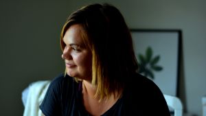 Sallu Högberg ser med andra ögon på arbetet i glasskiosk nu när hon fått lite distans. Kvinna i profil med mörkt hår i page. Hennes ansiktet lyses upp från ett fönster som inte syns i bild.