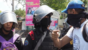 En ung demonstrant försöker förhandla med kravallpolis om att komma fram. I bakgrunden ett av otaliga enorma propagandaplakat med president Daniel Ortega och hustrun, vicepresident Rosario Murillo. En ung demonstrant försöker förhandla med kravallpolis om att komma fram. I bakgrunden ett av otaliga enorma propagandaplakat med president Daniel Ortega och hustrun, vicepresident Rosario Murillo.