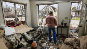 Kvinna ser ut genom ett fönster och ett tak som inte längre finns efter tornadon 2017 i Illinoi