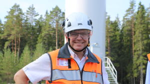 Jakob Kjellman. En man med skyddshjälm och orange väst står framför ett vindkraftverk.