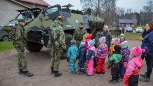 Barnen tyckte det var roligt att få se militärfordonet Pasi. Dagisbarn och soldater framför ett militärfordon.
