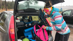 Ottossons helt egna rullande gym. Kvinna sätter träningsväska in i bakluckan på bilen