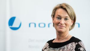 Mary Gestrin är kommunikationschef vid Nordiska rådet och ministerrådet i Köpenhamn. Porträttbild av Mary Gestrin, med oskarp Norden-logo i bakgrunden.