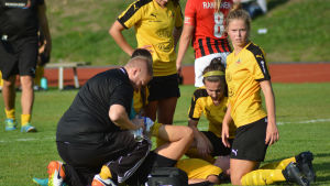 Amanda Kass och Chelsey Swackhamer hjälper till med skadade Jade Montgomery. Spelkamraterna hjälper den skadade Jade Montgomery.
