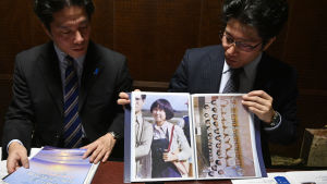 Megumi Yokotas bröder Testuva (tv) och Takuya tittar på ett gammalt familjefoto av sin syster. Kidnappade Megumis bröder håller upp foton av henne