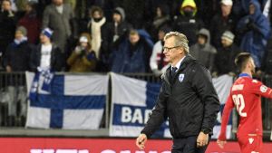 Markku Kanerva på väg att leda Finland till EM. Markku Kanerva går på en fotbollsplan. I bakgrunden syns Finlands flagga, något ur fokus.