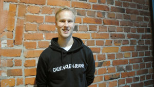 Vasa erbjuder goda möjligheter för samarbete över språkgränsen, tycker Niklas Valtonen, som är ekonomiansvarig för Vasa universitets studentkår. En ung man står framför en tegelvägg.