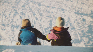 Lapset laskevat talvella mäkeä.