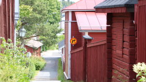 Kattpiskargränden i Kristinestad En smal gata som sluttar nedåt. På högra sidan om gatan röda trähus på rad.
