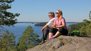 Linnavuorelta Linnansaaren kansallispuiston pääsaarelta aukeaa näkymä ympäröivälle Haukivedelle. Myös Linnasaaren kansaalispuistosta löytyy löylyjen lämpöä Saunapäivänä! Kaksi ihmistä istuu kalliolla ja katsoo Linnavuorelta Linnansaaren kansallispuiston pääsaarelta aukeaa näkymä ympäröivälle Haukivedelle.