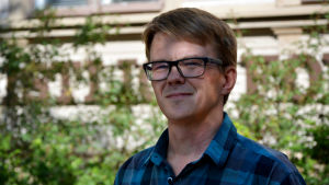 Thomas Swanljung. Vit man med glas ögon och blårutig skjorta kisar mot solen.