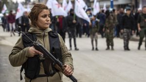 En kvinnlig kurdisk soldat vaktar en begravning i Qamishli. En kvinnlig kurdisk soldat vaktar en begravning i Qamishli
