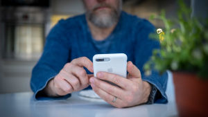 Mobilanvändarna skulle få ett direkt meddelande om de har varit i närheten av en person som smittats av coronaviruset. En man i närbild använder en mobiltelefon.