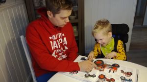 Sami och Alex läser bok. Alex behöver hjälp med allt på grund av sina skador. (Foto ur hemalbumet). Sami och Alex Dahlberg.