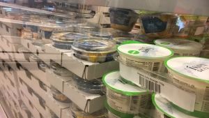 Mjölk och mjölkprodukter hör ofta till sortimentet i Karis. Yoghurtburkar och andra mjölproduktsburkar i en kyldisk bakom ett glas.