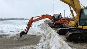 Grävmaskiner blandar snö som dumpats i havet vid Ärtholmen. Grävmaskiner blandar snö som dumpats i havet på Ärtholmen i Helsingfors.