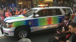 Polisen i New York har bett om ursäkt för handlingarna för 50 år sedan. Polisbilar i Pride-färger har anskaffats. Polisbil i folkmassa i New York med Pridefärger längs sidorna.