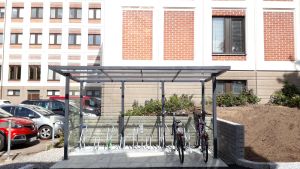 I augusti blev ett nytt cykeltak färdigt utanför Lojo stadshus. Där finns även laddningspunkter för två elcyklar. Ett cykelställ under ett tak intill en parkering.